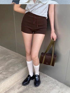 Detail view of dark brown knitted sports shorts with drawstring on a model outdoors