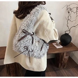 Detail of grey plush shoulder bag with brown leather bow tie on indoor model