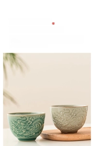 Macro detail of embossed dragon pattern on celadon ceramic teacups with wooden tray