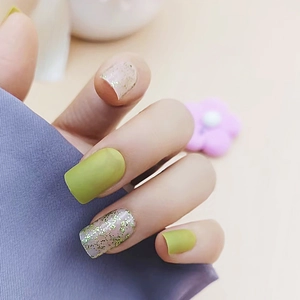 Short square matte green press-on nails with shimmering gold glitter detail