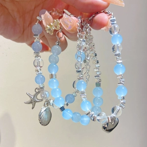 Dettaglio del bracciale con perline blu e ciondoli a forma di stella marina e conchiglia