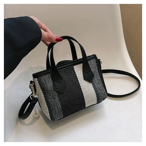 Close-up of black and white striped woven tote bag with adjustable shoulder strap detail