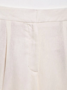 Macro shot of off-white linen vest and skirt set showing high-density stitching texture