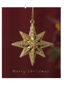 Detail of golden hollow star Christmas ornament with beaded texture on red background