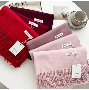 Detail of multi-color cashmere feel scarves with tassels in red and pink tones