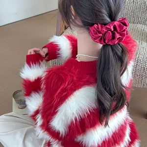 Detail of a large red silk scrunchie on brown hair with a cozy winter sweater
