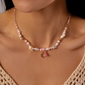Detail of bohemian pearl necklace with pink tassels and golden seashell charms