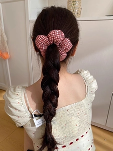 Detail of a red checkered sponge hair scrunchie worn on a ponytail for a sweet look