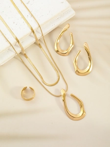 Artistic close-up of gold double-layer necklace, U-shaped earrings and ring set