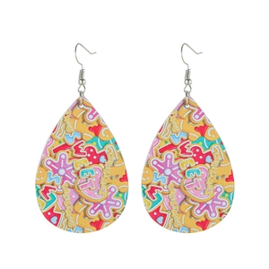 Detail of teardrop leather earrings with yellow gingerbread and candy cane patterns