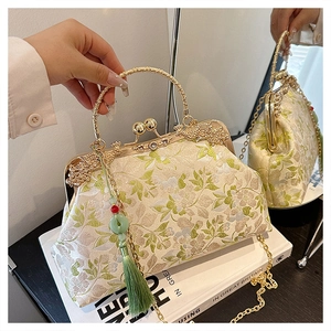 Detailed close-up of embroidered floral handbag with vintage metal kiss-lock and green tassel