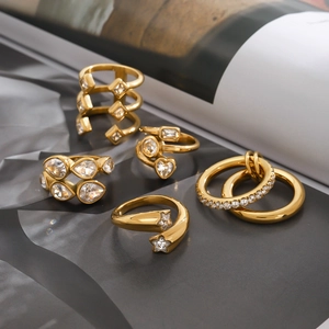 Set of five gold plated stainless steel rings with zircon stones on a dark book