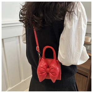 Detail of red bow-shaped crossbody bag featuring a soft padded aesthetic for women