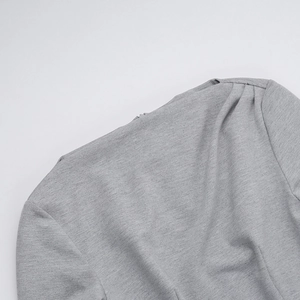 Close-up of fine grey knitted fabric showing detailed shoulder stitching and texture