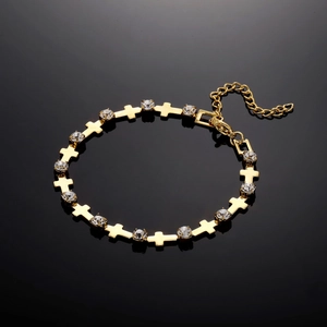 Close-up of golden cross link bracelet with cubic zirconia on black reflective surface