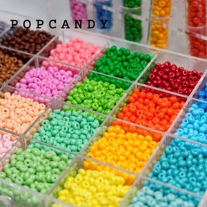 Macro shot of 2-4mm colorful glass seed beads organized in an acrylic storage box