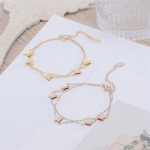 Close-up of dual-layer butterfly charms on gold and rose gold titanium steel bracelets
