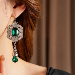 Close-up of vintage emerald water-drop earrings with intricate silver openwork carving