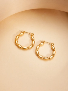 Detailed view of gold hoop earrings with beaded texture and polished mirror finish