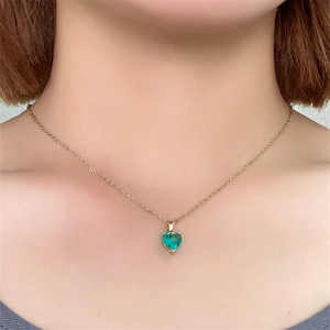 Close-up of a heart-shaped green zircon pendant with a delicate gold chain on a model