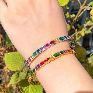 Elegant gold and silver rainbow zircon tennis bracelets worn on a wrist outdoors