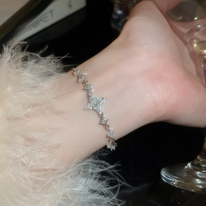 Close-up of a silver star bracelet with sparkling stones on a wrist with a soft background