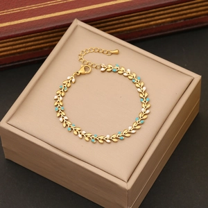 Gold wheat leaf bracelet with blue and white enamel inlay on a jewelry display box