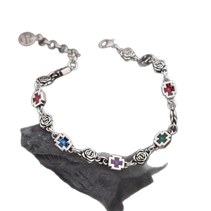 Vintage gothic silver bracelet with cross gemstones and rose-shaped charms on rock base