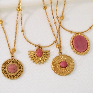 Vintage gold necklaces with pink rhodochrosite pendants on soft white fabric background