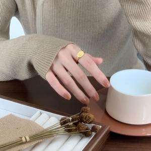 Detail of vintage gold sunburst signet ring on model hand with warm autumn background