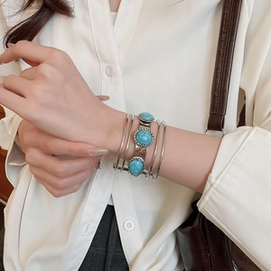 Detail of silver multi-layer metal bracelet with three turquoise stones on wrist