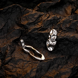 Artistic close-up of silver lava earrings with irregular molten texture on black paper