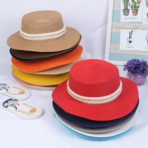 Detail of woven straw hats featuring pearl and gold chain bands in various summer colors