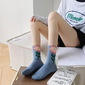 Close-up of blue cotton socks with 3D pink flower and green stem on a female model