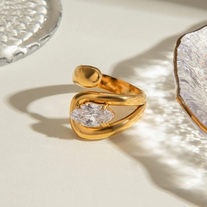 Modern gold stainless steel bypass ring with marquise-cut zircon on textured surface