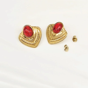 Detailed view of vintage gold plated butterfly earrings with red oval stones and wavy edges