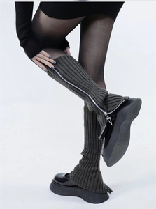 Detail of gray knitted leg warmers with vertical stripes and side zipper for boots