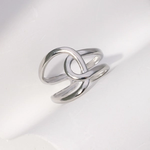 Macro view of geometric silver steel ring showing layered crossover open-end design