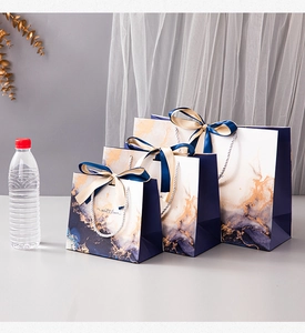 Three sizes of royal blue marble gift bags with navy ribbon bows and gold accents