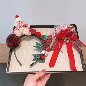 Christmas hair accessories featuring a bear headband and a red bow hair clip in a tray