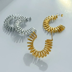 Detail of spiral spring C-shape earrings in gold and silver finish with metallic texture