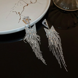 Detail of silver long tassel earrings with sparkling rhinestones on black background