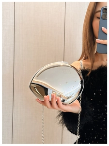 Detail of silver mirror acrylic egg-shaped handbag with a delicate metal chain strap