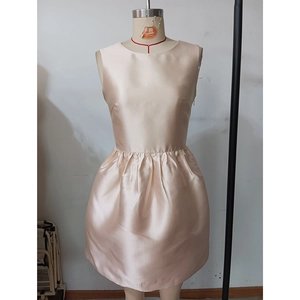 Détail de la robe en satin champagne avec plis élégants à la taille et tissu brillant