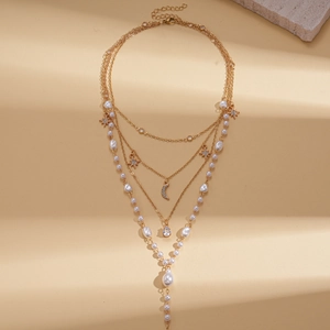 Detail of layered gold necklace with imitation pearls plus star and moon charms