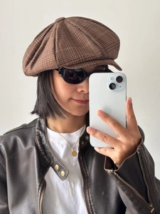 Detail of a brown plaid newsboy cap showing the classic octagonal shape and retro pattern