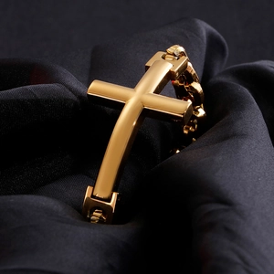 Detailed close-up of a gold-plated stainless steel cross bracelet on black silk