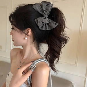 Detailed side view of a grey fabric bow hair claw clip with black butterfly print on hair