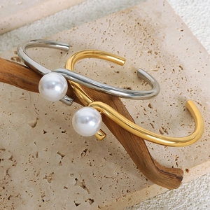 Elegant gold and silver titanium steel bangles with white pearls on a textured stone base