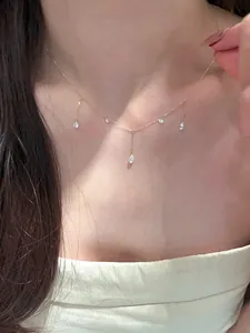 Close-up of gold chain necklace with five pear-cut zircon pendants on a model
